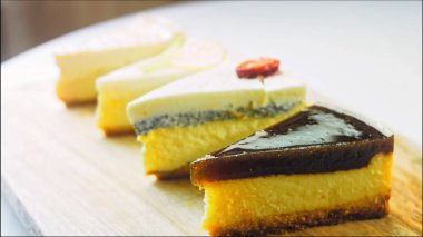 Arka arkaya dizilmiş dört çeşit cheesecake. Kaypak ve makro atış. Bir retro stil pişirme tahtası kullanılır.