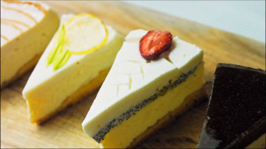 Arka arkaya dizilmiş dört çeşit cheesecake. Kaypak ve makro atış. Bir retro stil pişirme tahtası kullanılır.