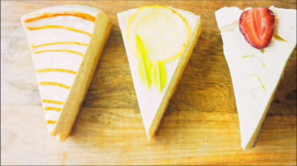 Four kinds of cheesecake arranged in a row. Slider and macro shooting. A retro style cooking board is used.