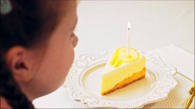 Retro tabakta limonlu cheesecake. Altın çatal ve bıçak kullan. Pastanın üzerindeki yanan mumu üfle. Doğum gününü kutluyoruz..