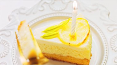 Retro tabakta limonlu cheesecake. Altın çatal ve bıçak kullan. Kadın pastaya yanan mumu koyar. Doğum gününü kutluyoruz..