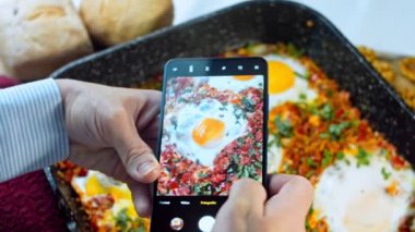 Telefonunuzla yemek fotoğrafları çekiyorsunuz. Gürcistan mutfağında kızarmış yumurta, chirbuli. Tavada domatesli yumurta..