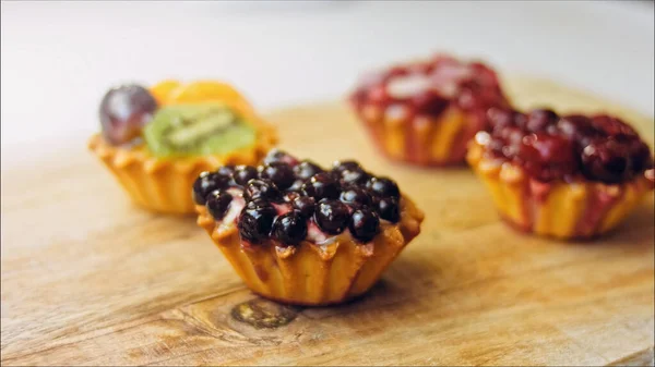 A variety of cake baskets with berries. The cakes are beautifully decorated on a retro-style cooking tray.