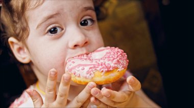 Kız hediyeler arasından seçiyor, parmağını işaret ediyor. Çikolata, marşmelov ve retro pişirme tepsisindeki şekerli çörekler. Donutlar doğal çikolatayla süslenmiş bir kağıdın üzerinde. Makro ve kaydırıcı