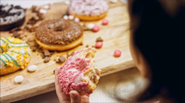 Kız hediyeler arasından seçiyor, parmağını işaret ediyor. Çikolata, marşmelov ve retro pişirme tepsisindeki şekerli çörekler. Donutlar doğal çikolatayla süslenmiş bir kağıdın üzerinde. Makro ve kaydırıcı