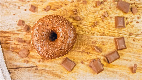 Chocolate donuts decorated with chocolate pieces. Donuts are on a paper decorated with natural chocolate. Macro and slider shooting. Bakery and food concept. Various colorful donuts. Chocolate, pink