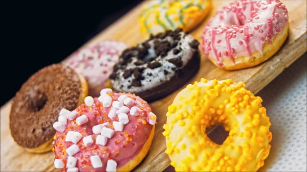 Chocolate, marshmello and candy donuts on a retro baking tray. Donuts are on a paper decorated with natural chocolate. Macro and slider shooting. Various colorful donuts. Chocolate, pink, blue donuts.