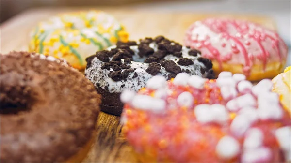 Chocolate, marshmello and candy donuts on a retro baking tray. Donuts are on a paper decorated with natural chocolate. Macro and slider shooting. Various colorful donuts. Chocolate, pink, blue donuts.