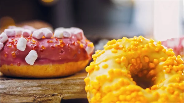 Chocolate, marshmello and candy donuts on a retro baking tray. Donuts are on a paper decorated with natural chocolate. Macro and slider shooting. Various colorful donuts. Chocolate, pink, blue donuts.