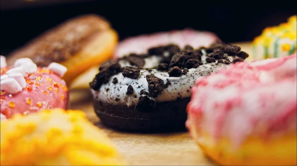 Chocolate, marshmello and candy donuts on a retro baking tray. Donuts are on a paper decorated with natural chocolate. Macro and slider shooting. Various colorful donuts. Chocolate, pink, blue donuts.