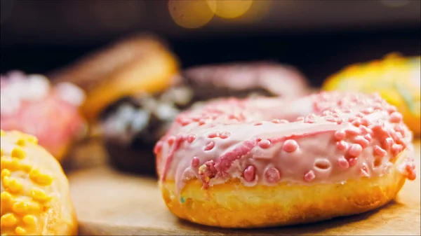 Chocolate, marshmello and candy donuts on a retro baking tray. Donuts are on a paper decorated with natural chocolate. Macro and slider shooting. Various colorful donuts. Chocolate, pink, blue donuts.