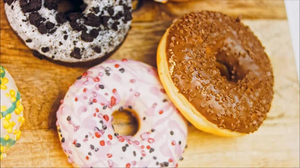 Chocolate, marshmello and candy donuts on a retro baking tray. Donuts are on a paper decorated with natural chocolate. Macro and slider shooting. Various colorful donuts. Chocolate, pink, blue donuts.