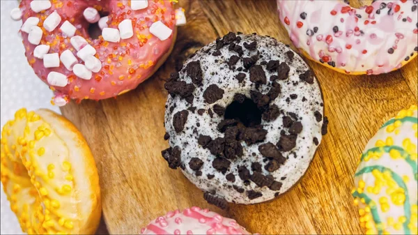 Chocolate, marshmello and candy donuts on a retro baking tray. Donuts are on a paper decorated with natural chocolate. Macro and slider shooting. Various colorful donuts. Chocolate, pink, blue donuts.