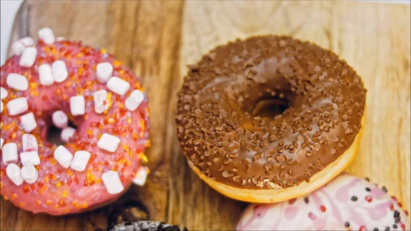 Chocolate, marshmello and candy donuts on a retro baking tray. Donuts are on a paper decorated with natural chocolate. Macro and slider shooting. Various colorful donuts. Chocolate, pink, blue donuts.