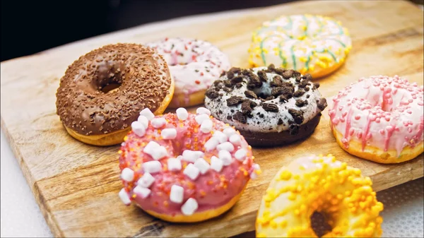 Chocolate, marshmello and candy donuts on a retro baking tray. Donuts are on a paper decorated with natural chocolate. Macro and slider shooting. Various colorful donuts. Chocolate, pink, blue donuts.
