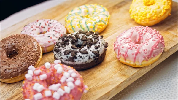 Chocolate, marshmello and candy donuts on a retro baking tray. Donuts are on a paper decorated with natural chocolate. Macro and slider shooting. Various colorful donuts. Chocolate, pink, blue donuts.