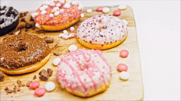 Chocolate, marshmello and candy donuts on a retro baking tray. Donuts are on a paper decorated with natural chocolate. Macro and slider shooting. Various colorful donuts. Chocolate, pink, blue donuts.