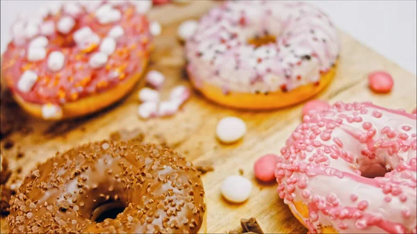 Chocolate, marshmello and candy donuts on a retro baking tray. Donuts are on a paper decorated with natural chocolate. Macro and slider shooting. Various colorful donuts. Chocolate, pink, blue donuts.