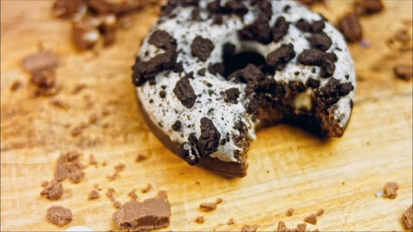 多努特有一个嘴巴状的咬痕 巧克力甜甜圈 上面装饰着一些意大利饼干 甜甜圈在用天然巧克力装饰的纸上 宏观和滑翔机射击 面包店和食品概念 — 图库照片
