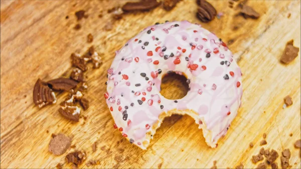 Pink donuts decorated with pink icing. Donuts are on a piece of paper decorated with candy. Macro and slider shooting. The candies move in slow motion. Bakery and food concept. Various colorful donuts