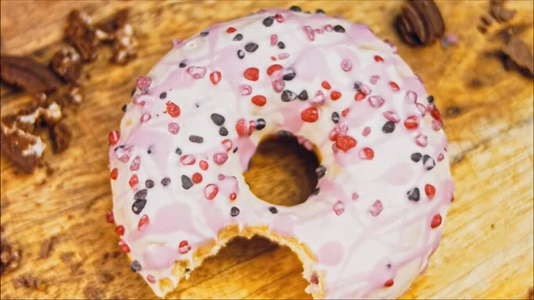 Pink donuts decorated with pink icing. Donuts are on a piece of paper decorated with candy. Macro and slider shooting. The candies move in slow motion. Bakery and food concept. Various colorful donuts