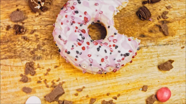 Pink donuts decorated with pink icing. Donuts are on a piece of paper decorated with candy. Macro and slider shooting. The candies move in slow motion. Bakery and food concept. Various colorful donuts