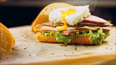 Fransız ekmeği, peynir, salata yaprakları ve sosisle sanvich 'in üzerinde kaynayan kalp şeklinde sahanda yumurta. Kaydırıcı atışı.