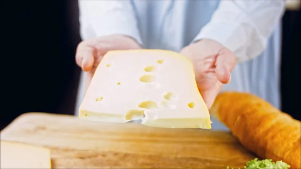 女性は手に穴のあるチーズを持っている スライダーはチーズのプレゼンテーションプロセスを撮影 — ストック写真