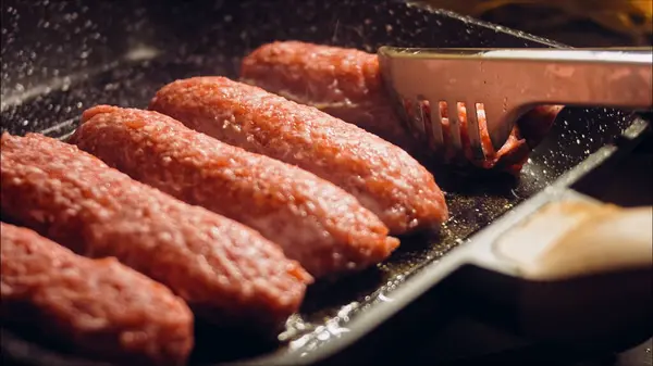 Cook Returns Food Tongs Pink Sausages Fried Grill Pan Sausages — Stock Photo, Image