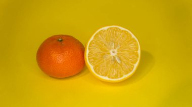 Sarı arka planda dilimlenmiş limon ve mandalina. Citrus meyveleri.
