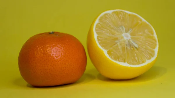 Kawałek cytryny i mandarynki, na żółtym tle. Owoce cytrusowe. — Zdjęcie stockowe