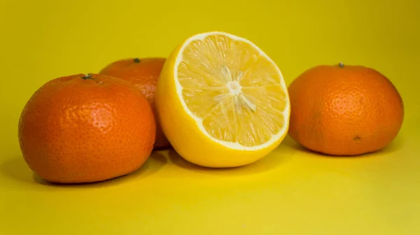 Kawałek cytryny i mandarynki, na żółtym tle. Owoce cytrusowe. — Zdjęcie stockowe