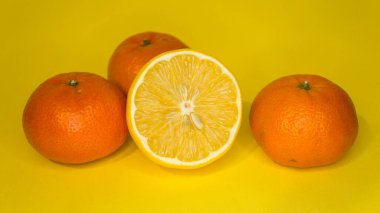 Sarı arka planda dilimlenmiş limon ve mandalina. Citrus meyveleri.