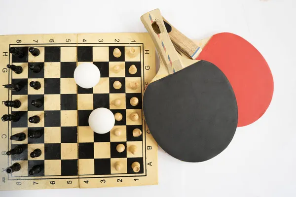 乒乓球在棋盘前的球拍 球上有球片和白色背景的乒乓球 — 图库照片