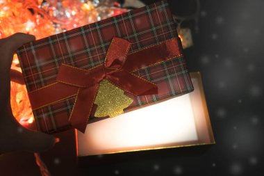 Kırmızı fiyonklu ve İskoç kafesli dikdörtgen bir hediye kutusu. Güzel bir pakette Noel hediyesi. Noel ağacı çelengi