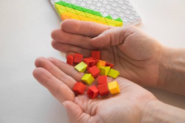 Tasarımcının bir sürü renkli plastik parçasını elinde tutuyor. Gökkuşağı elementleri ellerinde. Bir çocuk için geleceğin mesleğini seçmek. Erken çocuk gelişimi yöntemleri