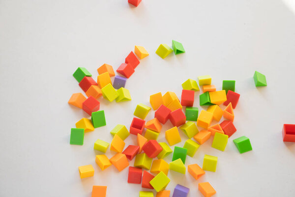 He holds a lot of colorful plastic parts of the designer in his hands. Rainbow elements in the hands. Choosing a future profession for a child. Methods of early child development