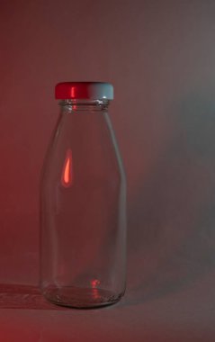 Siyah arka planda beyaz kapaklı cam bir süt şişesi. Neon kırmızı lamba. Boş maket yap