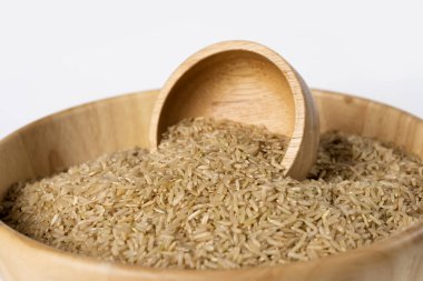 Beyaz arka planda bir kasede çiğ kahverengi pirinç. Seçici odak.