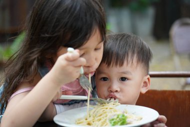 Asyalı oğlanlar ve kızlar lezzetli spagetti yiyorlar. Kız ve erkek kardeş spagetti yiyorlar.