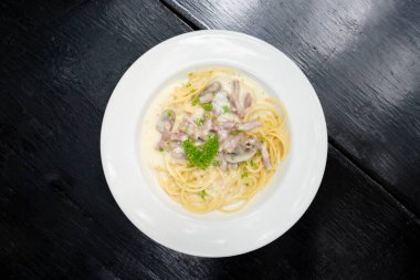 Siyah ahşap arka planda beyaz tabakta spagetti, spagetti menüsü konsepti. Üst görünüm.