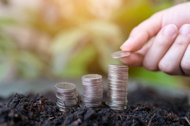 Kadının eli yeşil doğalı gümüş sikkelerin üzerine gümüş sikkeler koyuyor. para tasarrufu ve işletme finans kavramı, iş büyümesi ve para geleceği, mali başarı