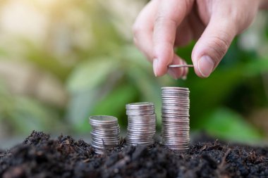 Kadının eli yeşil doğalı gümüş sikkelerin üzerine gümüş sikkeler koyuyor. para tasarrufu ve işletme finans kavramı, iş büyümesi ve para geleceği, mali başarı