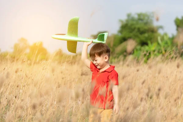 boy happy playing with toy plane in nature and clear morning sky, Child concept and dream plane to become pilot. want to fly like an airplane