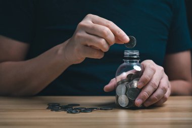 İş adamı parayı domuz kumbarasında masanın üzerinde sakladı. finansal istikrar yönetimi konsepti. Tasarruf ve emekli aylıkları, para toplama, mali planlama