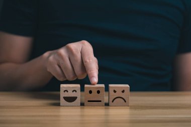 Müşterinin eli kötü bir gülümseme kartı, servis puanı ve tatmin konseptiyle yorum yaptı. sembol geribildirim ölçekli ifade üzgün ve kötü servise kadar mutludur