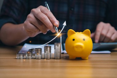 İş adamı Forex ticaret grafiği finansal verilerini analiz ediyor. Kumbarada para ve masasında çizelgeler olan oklar. Para büyümesi ve iş finansmanı kavramı, başarılı yatırım stratejisi