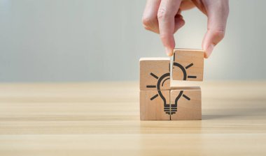 Idea and creativity concept. Hand of business selected wooden cube block with light bulb icon symbol and icon question mark creative concept. new ideas