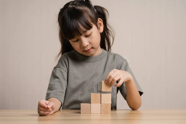 Girls build wooden cubes in layers with wooden blocks cube wooden box. girl playing with wooden block toys. Concept of early child development