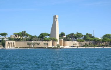 Liman bölgesinde görülebilen faşist dönem dümeni şeklinde İtalyan denizcilerine dikilen anıt, en üstteki oyukta Madonna 'nın heykeli, Brindisi' nin heykeli bulunuyor.